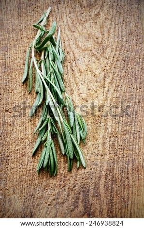 sprigs of rosemary on a wooden board top view vertical format