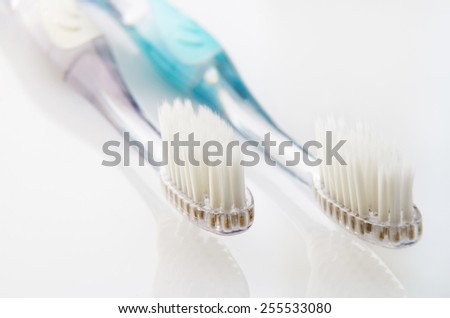 white and turquoise toothbrushes on white table. horizontal