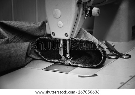 sewing machine and jeans in sewing workshop. monochrome, horizontal