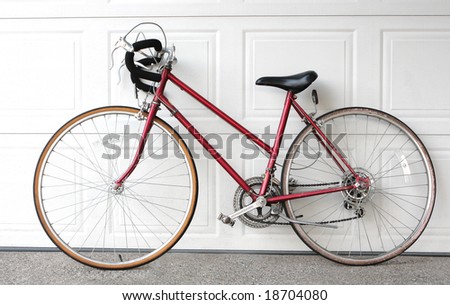 bicycle leaning over a garage door on drive way