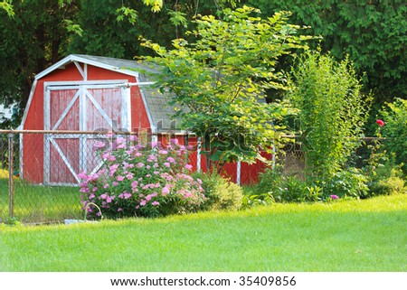 Small red barn in the yard beyond the fence