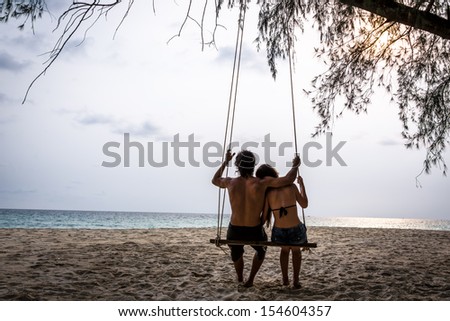 Happy Couple In Love On A Swing Looking At The Ocean. Koh Kood Island, South East Asia. Thailand.