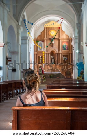 Religious scene young female praying at local church in Mexico.