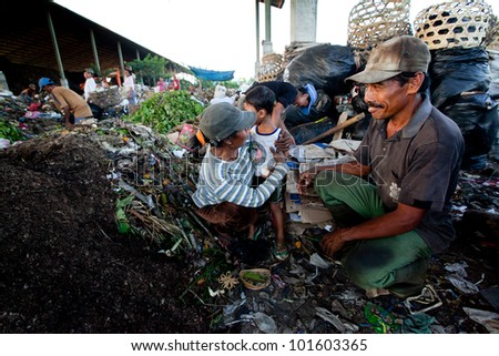 BALI, INDONESIA - APRIL 11: Unidentified children and his parents working in a scavenging at the dump on April 11, 2012 on Bali. Bali daily produced 10,000 cubic meters of waste.