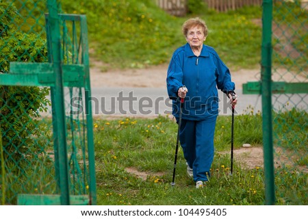 Active old woman (85 years old) nordic walking outdoors.