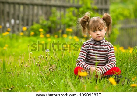 Funny lovely little five-year girl sitting in grass