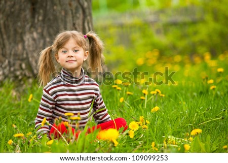 Enthusiastically surprised lovely little five-year girl sitting in grass
