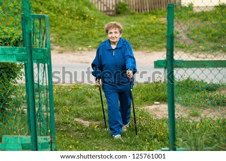 Active old woman nordic walking outdoors, 85 years old.