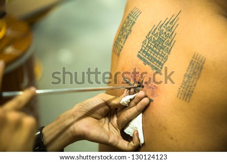 NAKHON CHAI, THAILAND - MAR 1: Unidentified monk makes traditional Yantra tattooing on Mar 1, 2012 in Nakhon Chai, Thailand. Yantra tattoo also called Sak Yant, practiced in Southeast Asian countries.