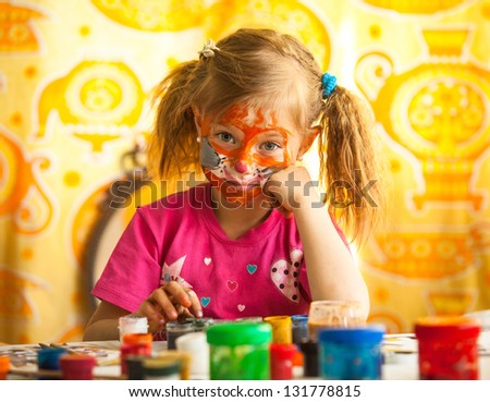 Emotional little child, drawing paint with paint of face