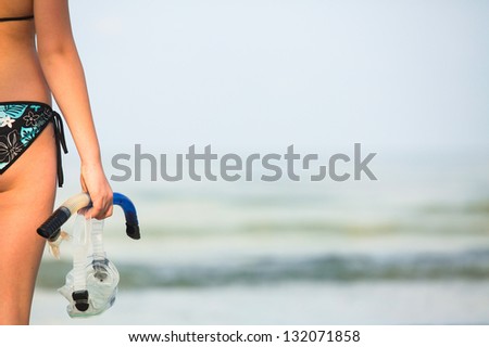 Snorkeling or diving, young woman with a snorkel and mask standing on sand and going to swim in sea (picture with space for text)