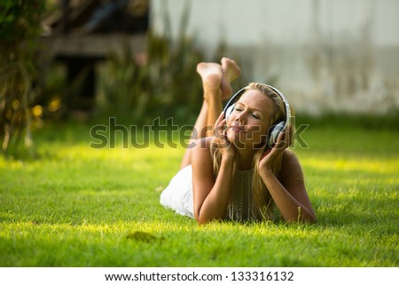 Emotional lovely girl with headphones enjoying nature and music at sunny day.