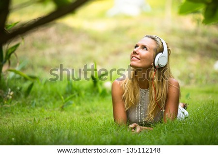 Lovely girl with headphones enjoying nature and music at sunny day.