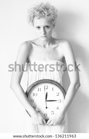 Scrawny girl with big clock in hands, black and white photo.