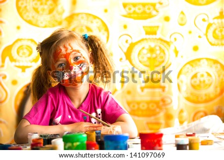 Little child drawing paint with paint of face.
