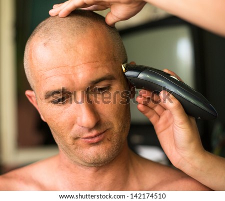 Close-up: Hairdresser shaving man with hair trimmer.