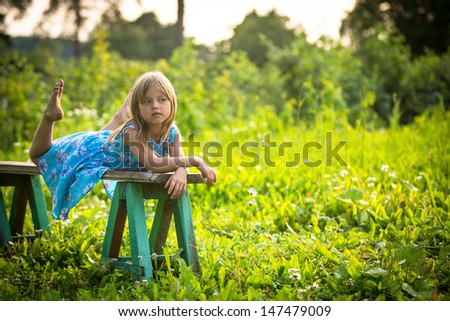 Charming little girl in the yard of a country house