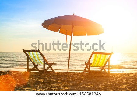 Beach loungers on deserted coast sea at sunrise.
