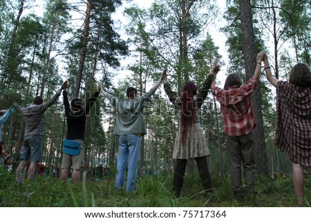 PSKOV REGION, RUSSIA - JULY 19: Members of the Russian Rainbow Family (Youth counterculture 1960\'s: bohemianism, hipster and hippie culture) hold hands in a circle during an annual gathering near Lake Asho on July 19, 2010 in Pskov Region, Russia.