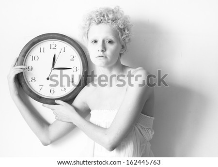 Conceptual portrait of woman with big clock, black and white photo.