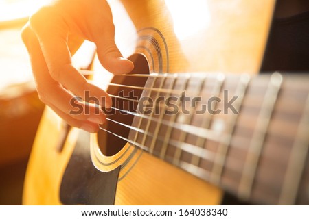 Female hand playing on acoustic guitar. Close-up.