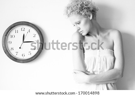 Young tender girl with big clock, black and white photo.