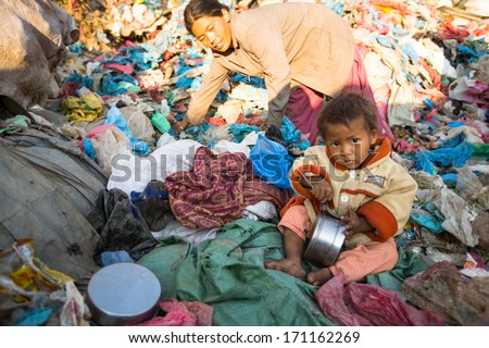 KATHMANDU, NEPAL - DEC 22: Unidentified child is sitting while her parents are working on dump, Dec 22, 2013 in Kathmandu, Nepal. In Nepal annually die 50,000 children, in 60% of cases -malnutrition.