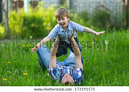 Father Playing With His Small Son In The Grass.