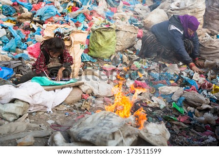 Kathmandu, Nepal - Dec 19: Unidentified Child Is Sitting While Her Parents Are Working On Dump, Dec 19, 2013 In Kathmandu, Nepal. In Nepal Annually Die 50,000 Children, In 60% Of Cases -Malnutrition.