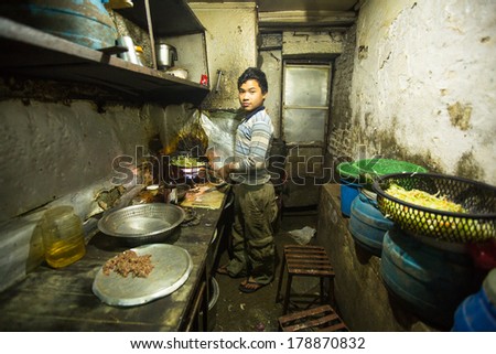 KATHMANDU, NEPAL - DEC 5, 2013: Unidentified boy from poorer area working in the kitchen dining room. About 2.6 million children in Nepal should work to ensure the survival of family.
