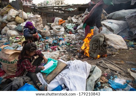 KATHMANDU, NEPAL - DEC 19, 2013: Unidentified child is sitting while her parents are working on dump. In Nepal annually die 50,000 children, in 60% of cases - malnutrition.