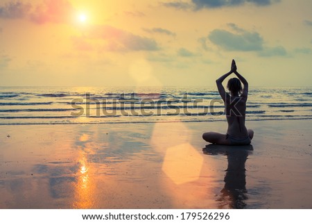 Silhouette of a woman yoga on sea sunset.