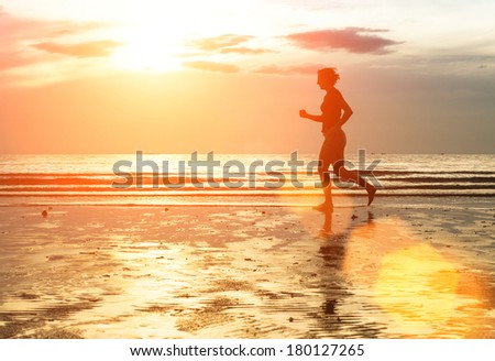 Silhouette of woman jogger at sunset on seashore.