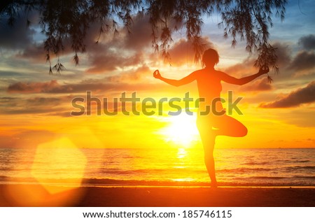 Yoga tree pose by woman silhouette with sunset sky background.