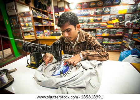 KATHMANDU, NEPAL - DEC 20, 2013: Unidentified Nepali man does embroidery on clothes in a small workshop. Nepal is one of poorest and least developed countries of the world, unemployment rate of 46 %.