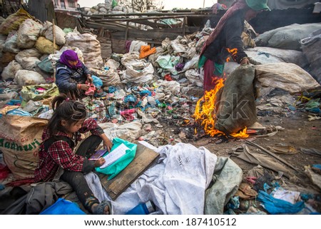 KATHMANDU, NEPAL - DEC 19: Unidentified child is sitting while her parents are working on dump, Dec 19, 2013 in Kathmandu, Nepal. In Nepal annually die 50,000 children, in 60% of cases -malnutrition.