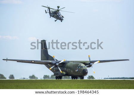 BERLIN, GERMANY - MAY 21, 2014: Transport plane C-160 Transall starts and Tiger combat helicopter go behind machine in position and secure launch from the air, demonstration at ILA Berlin Air Show.