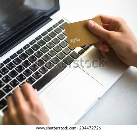 Discount card in a female hand, during shopping through Internet.