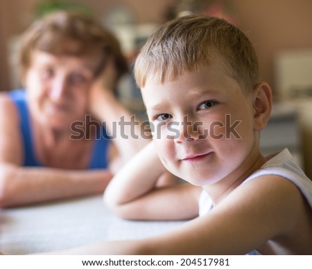 Funny little boy looking at the camera (grandmother to blured in the background)
