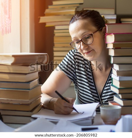 Intellectual woman writes on a notebook in a room with lots of books.