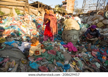 KATHMANDU, NEPAL - DEC 22, 2013: Unidentified child is sitting while her parents are working on dump. In Nepal annually die 50,000 children, in 60% of cases - malnutrition.