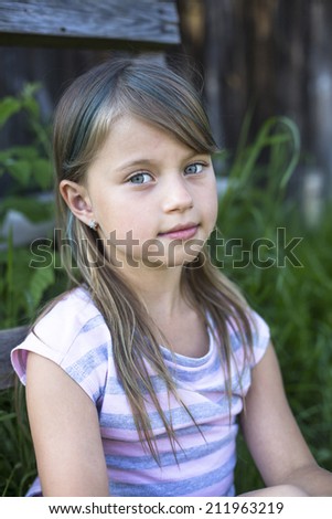 Portrait of cute little girl near a country house.