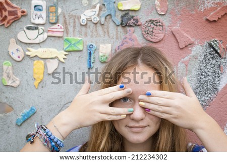 Cute cheerful young girl covers his eyes with his hands.