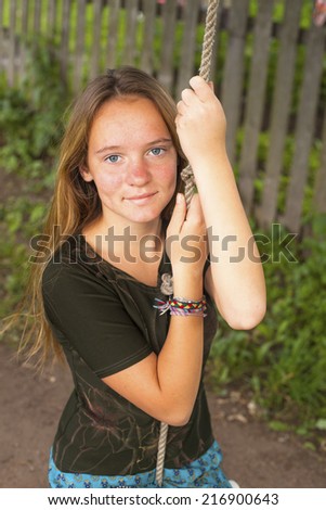 Nice teen girl swinging on a rope-swing in the countryside.