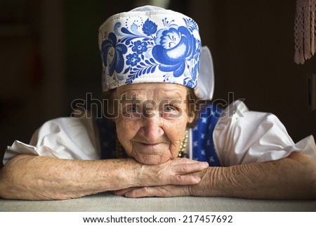 Old woman in traditional folk costume in  his house, close-up portrait.