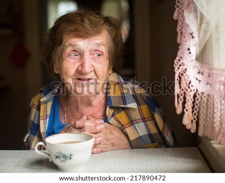 Old woman emotionally talking sitting near the window in his country house.