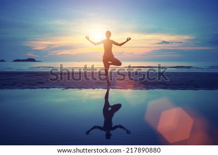 Young yoga woman meditation on the beach at sunset.