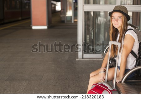 Cute young girl waits for train at the railway station.