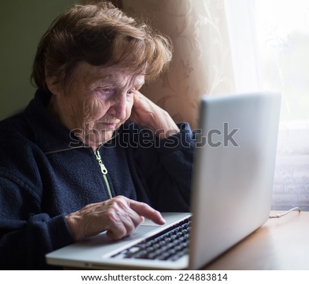 Old woman typing on laptop keyboard.