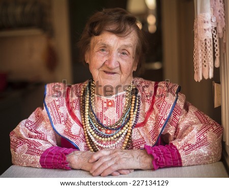 Old woman in ethnic clothes at home in the village.
